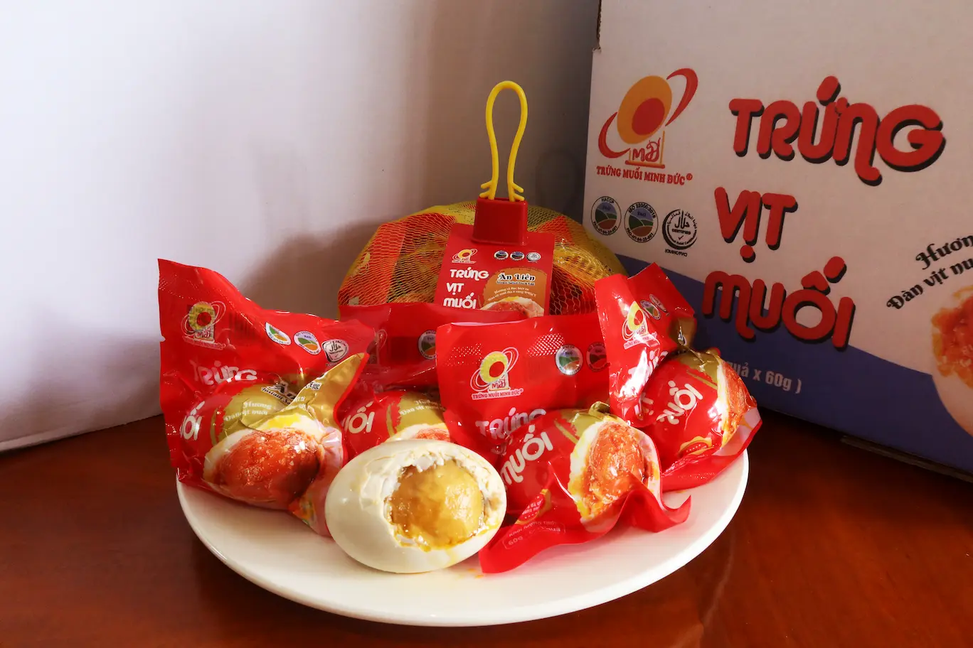 Minh Duc packaged salted duck eggs on a white plate with a peeled egg showing rich golden yolk and branded box.